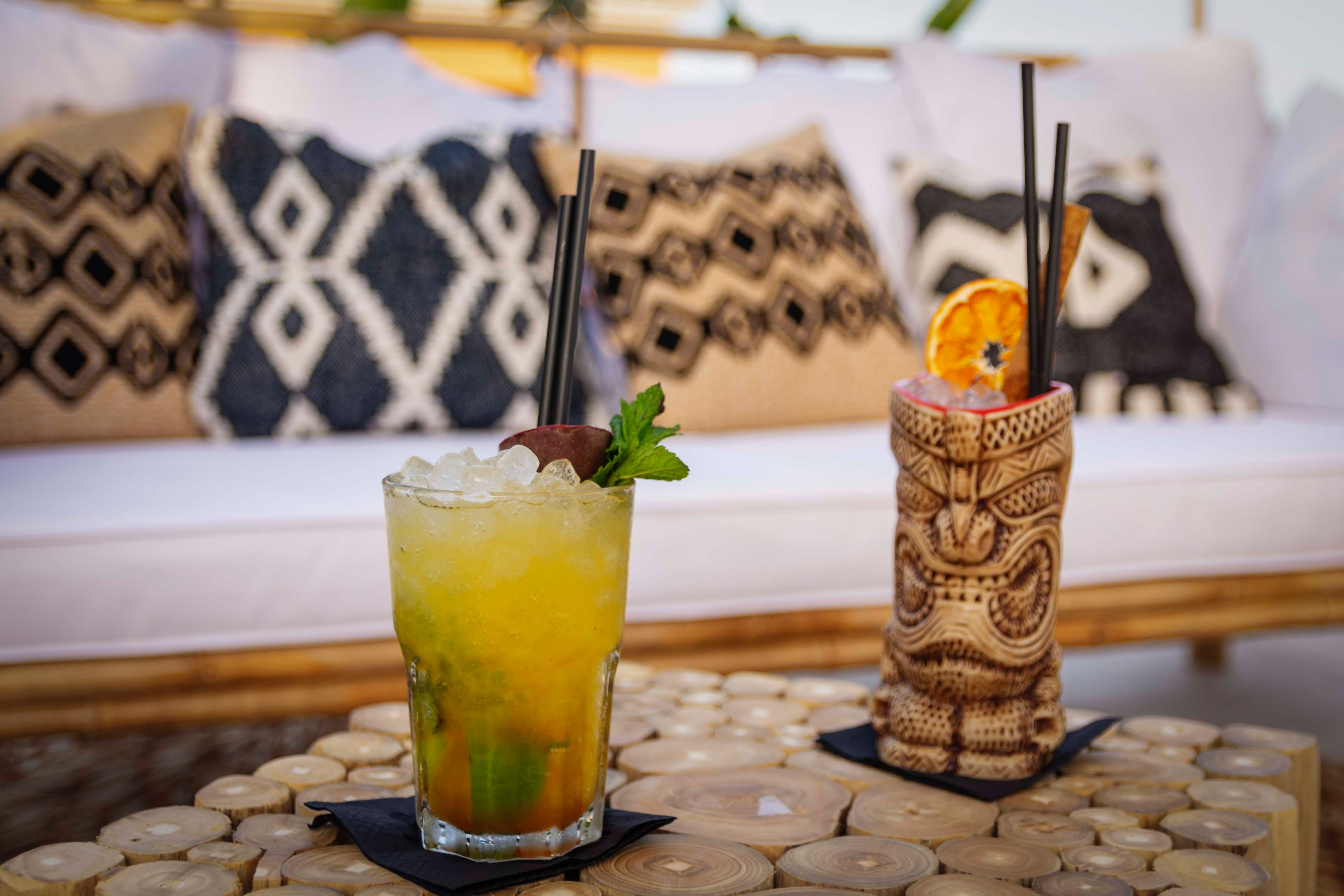 two tiki drinks in front of a comfy couch